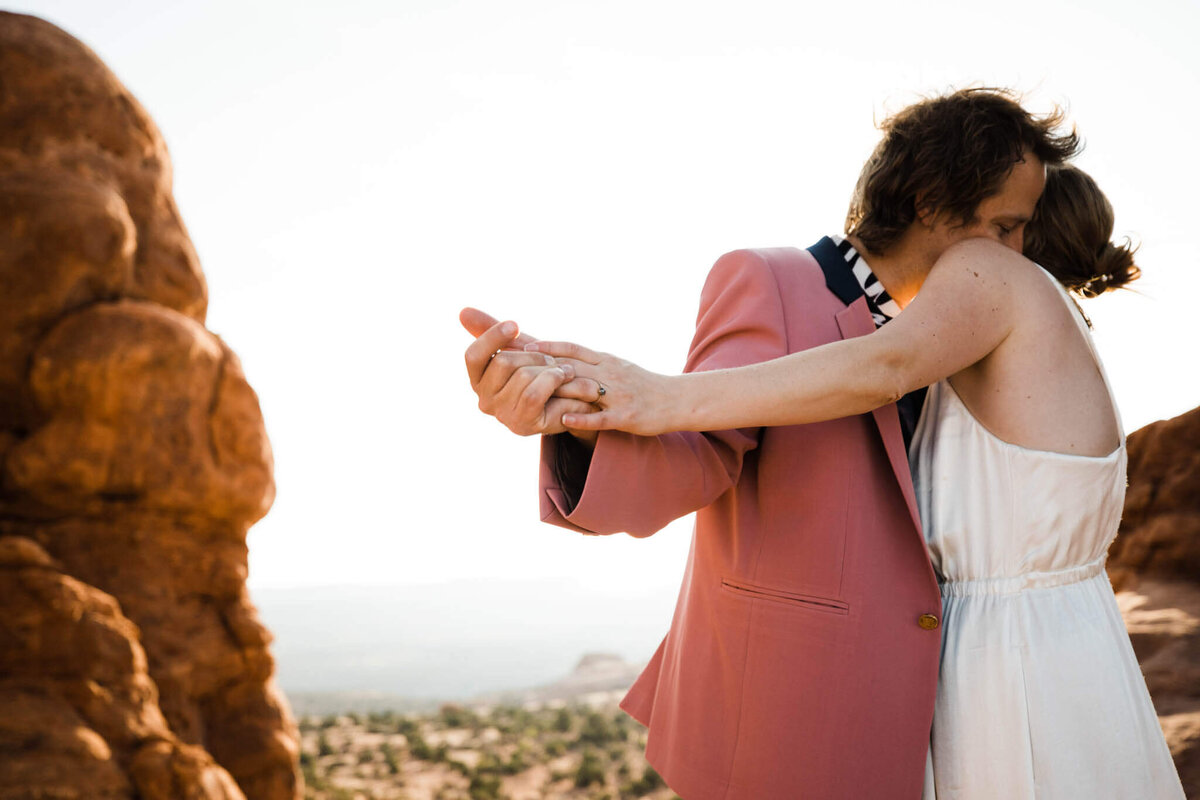 in the arizona desert the groom kisses brides head with a storm gathering behind the,