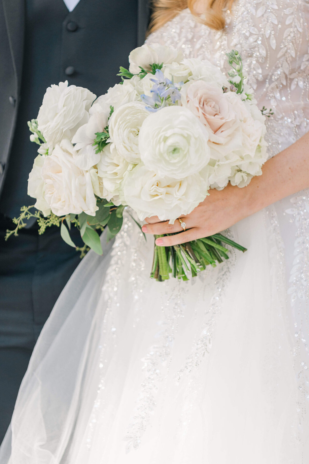 Close up of brides hand holding wedding bouquet of white and pastel flowers
