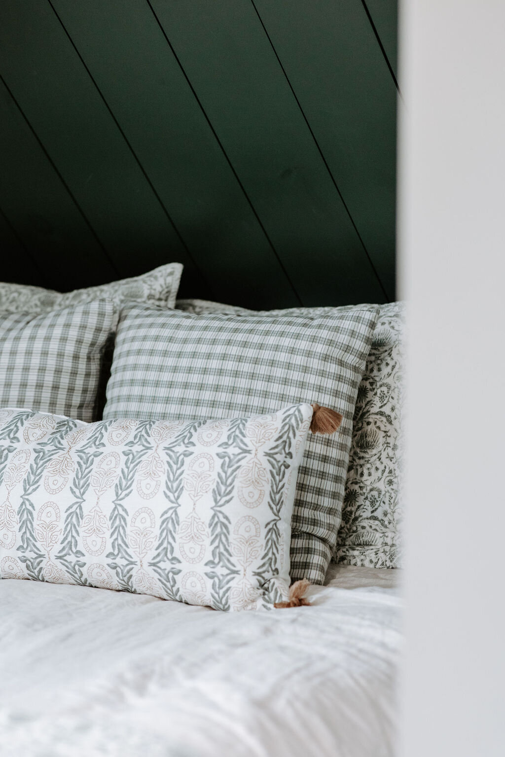 the bed with green studio mcgee pillows and linens against a dark olive shiplap wall in the Willowbrook wedding venue overnight suite