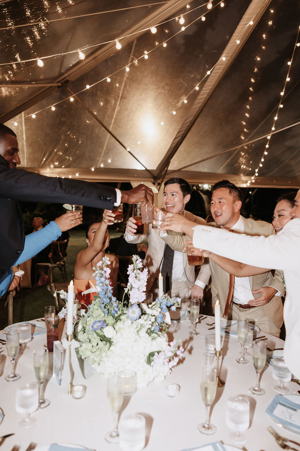 wedding guests at round table standing up to cheers each other
