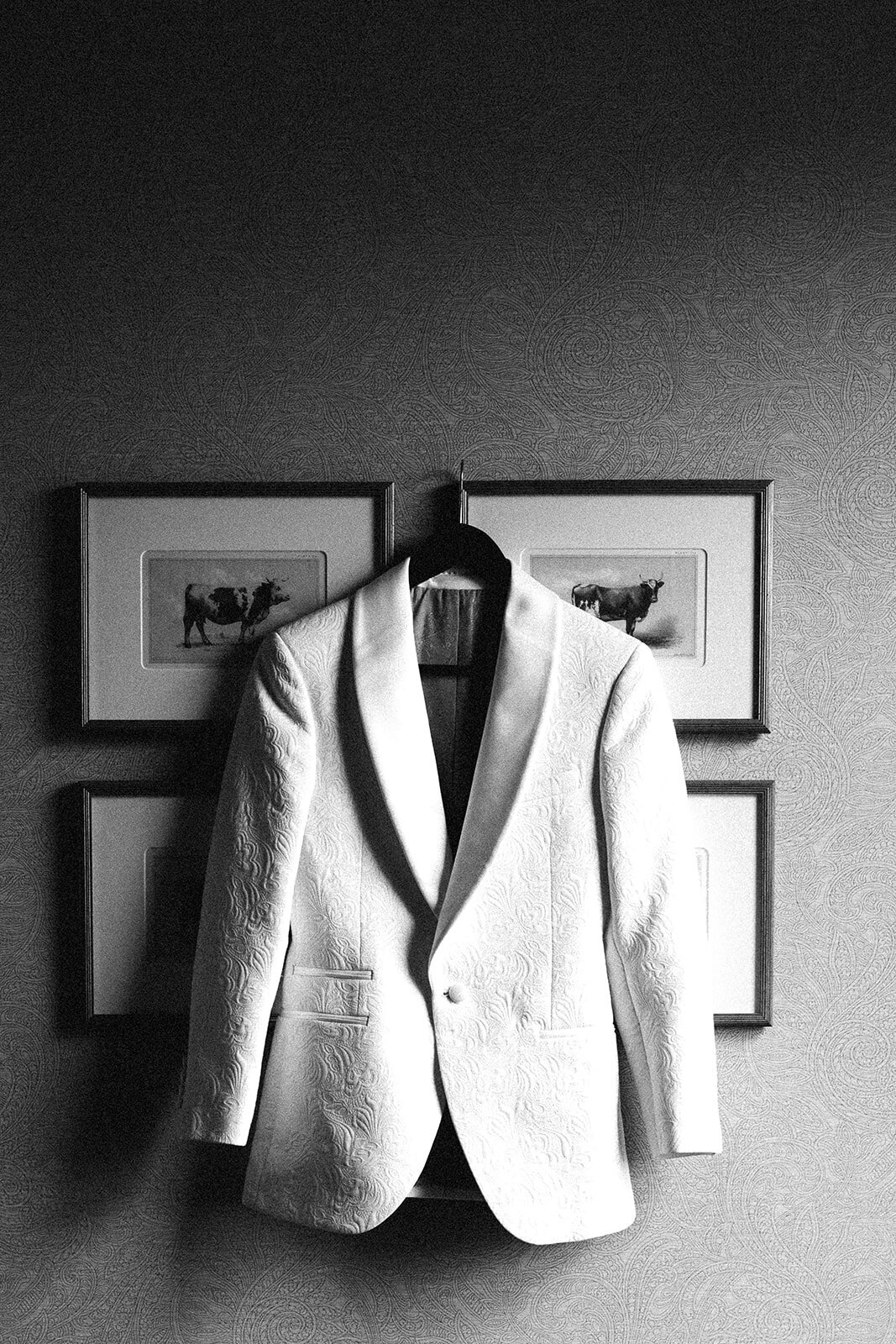 Wedding Photography, black and white image of grooms suit jacket hanging up on the wall
