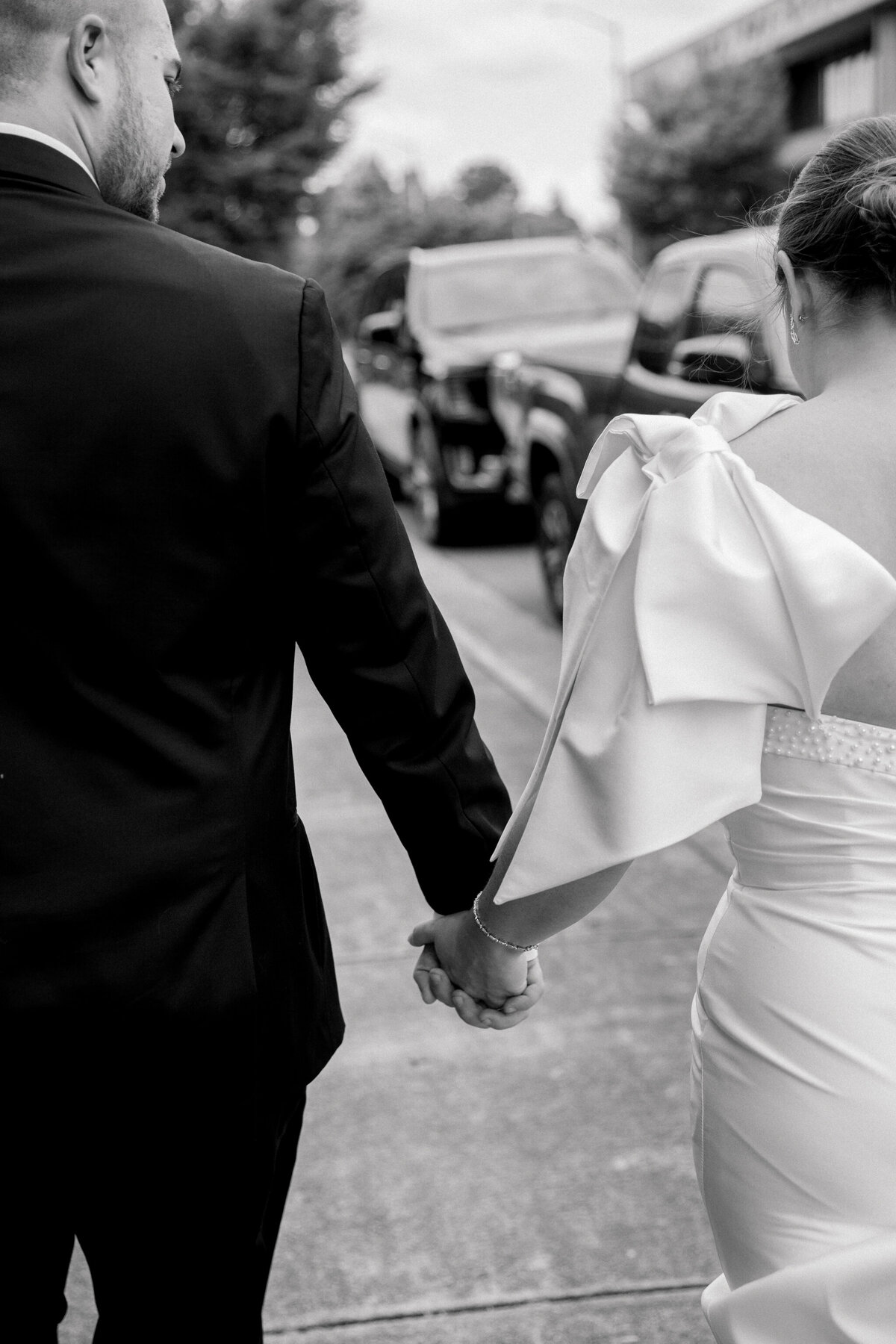 Black and white image of bride and groom walking down the street to the Bristol Train Station