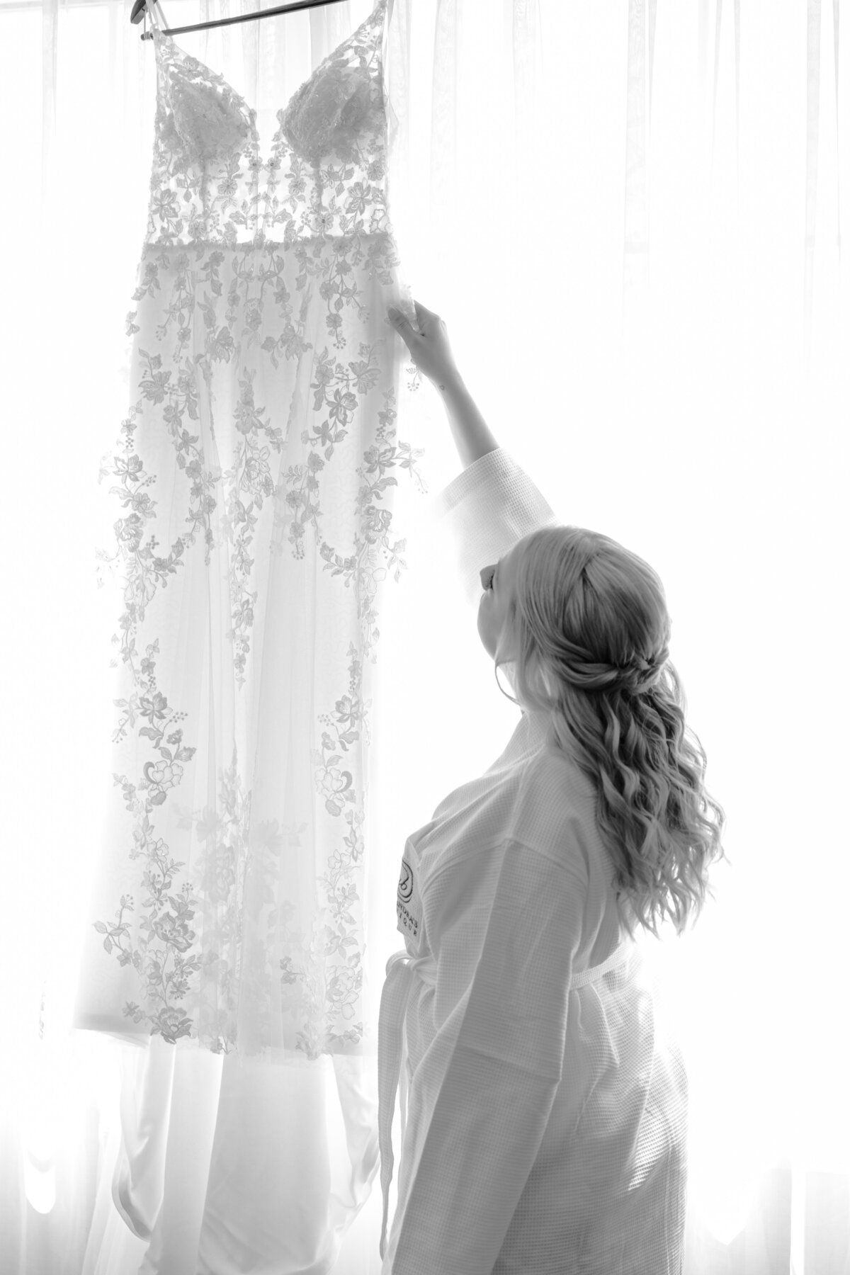 black and white image of bride looking at wedding dress