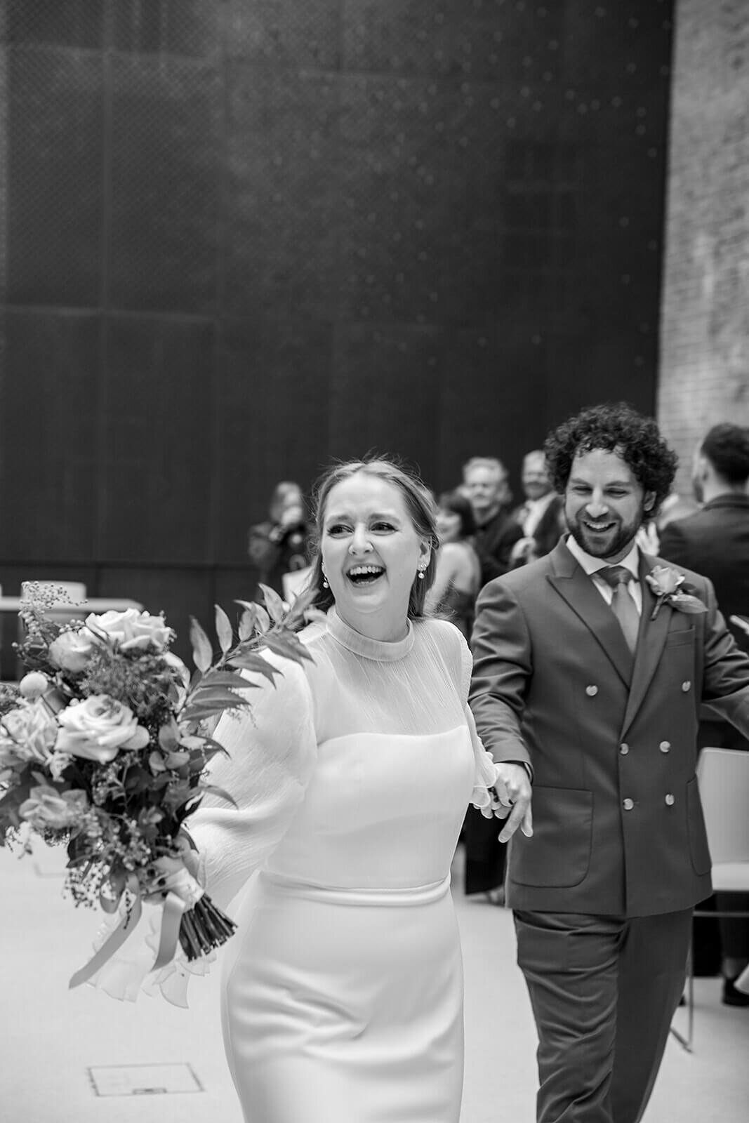 Bride running down aisle  with groom at Hackney Town Hall