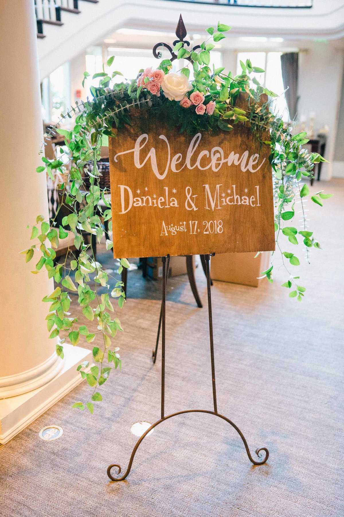 Lush greens and rose clusters decorate this welcome sign