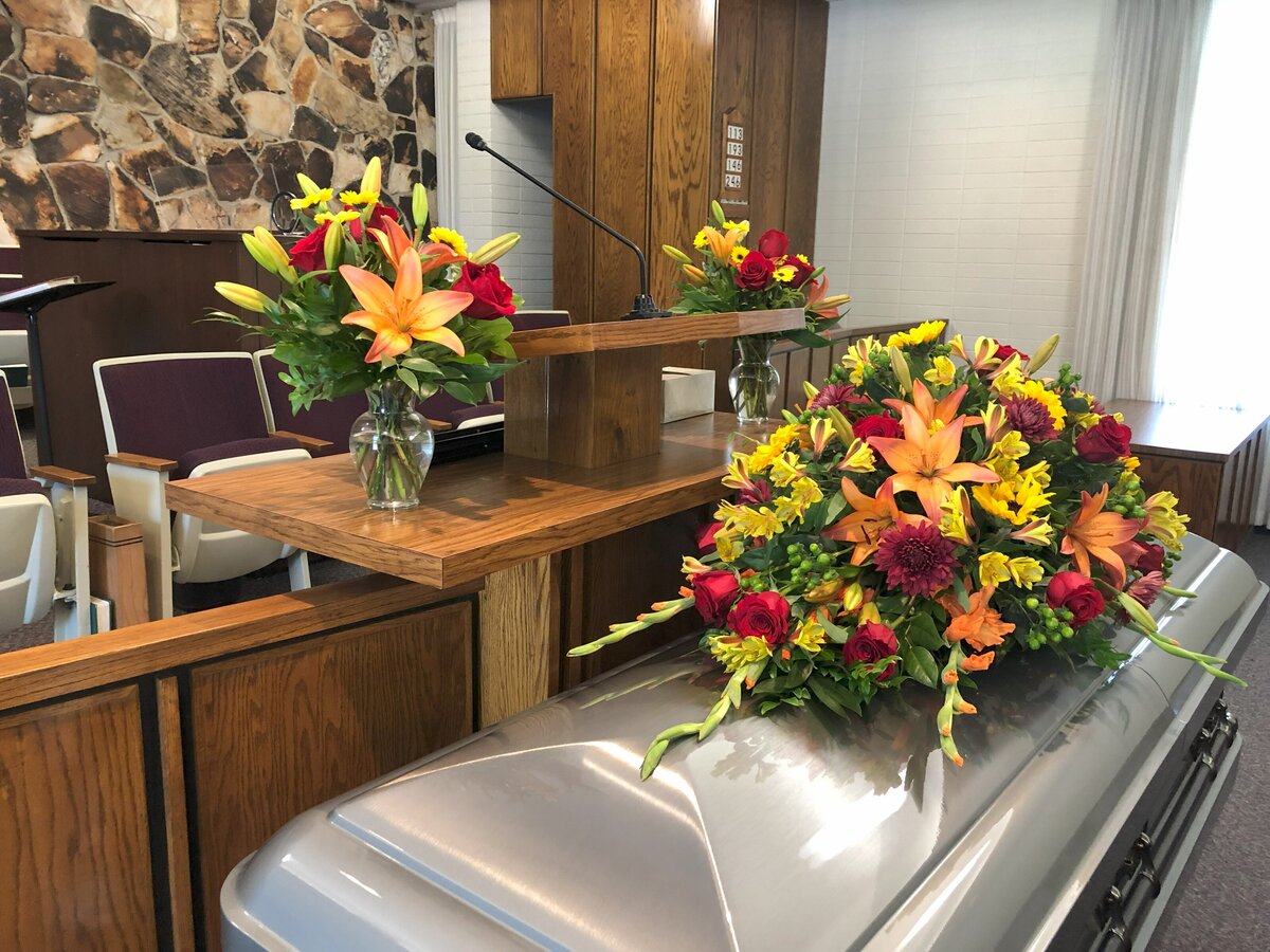 funeral casket spray in red yellow and orange color scheme