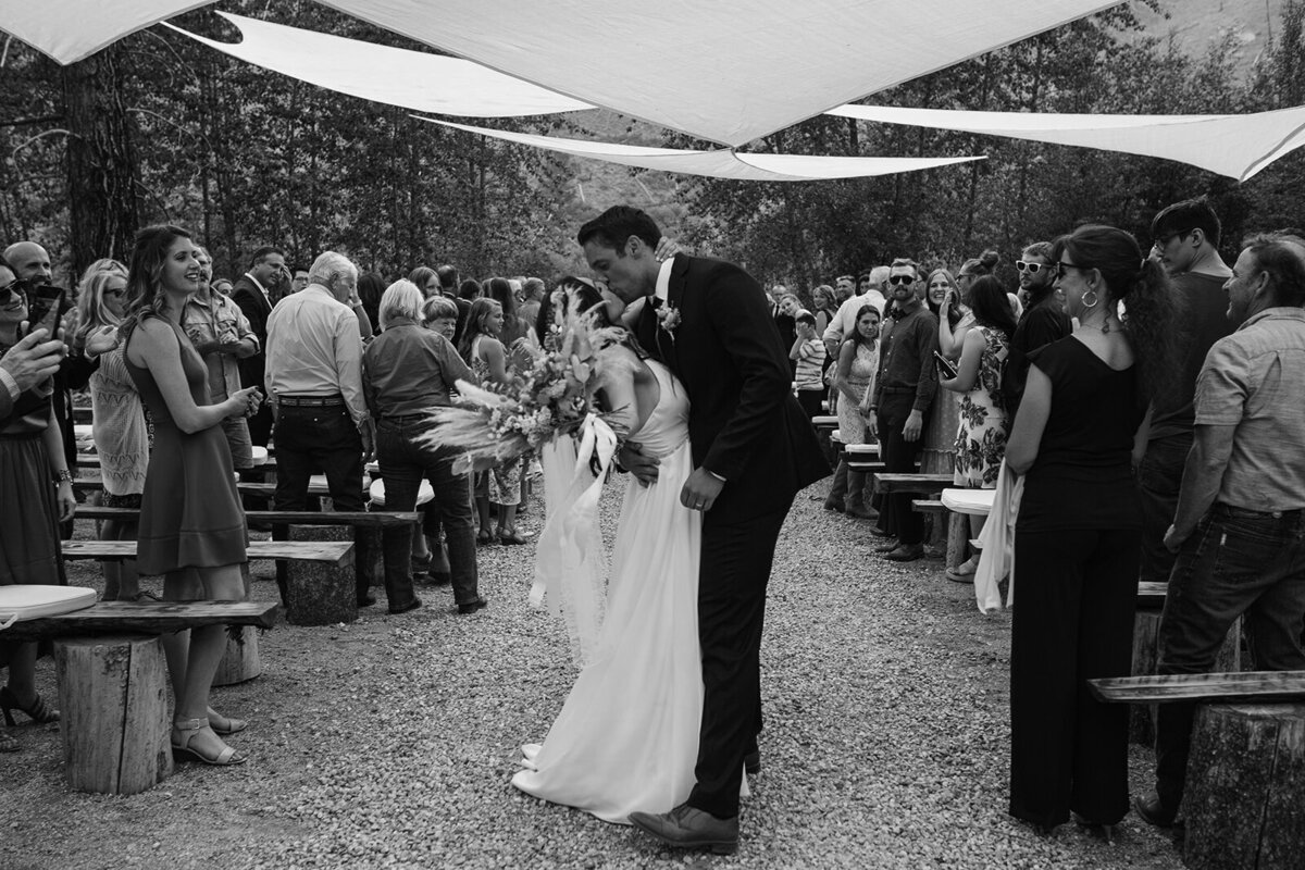 bride and groom kiss while guests celebrate