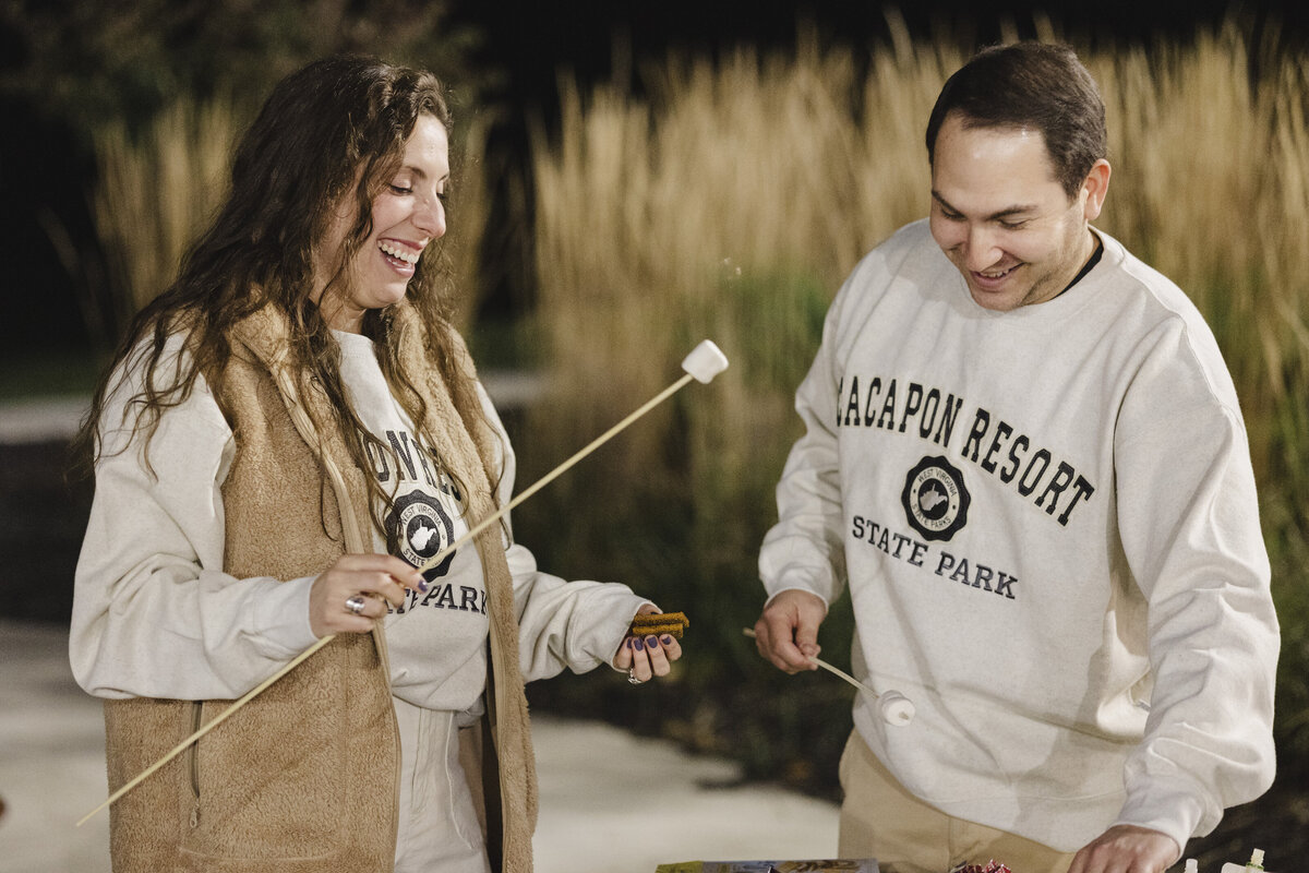 Two people make s'mores at a rehearsal dinner.