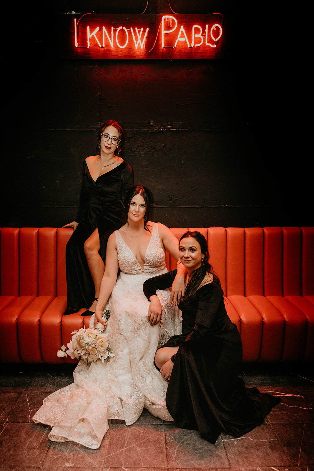 Bride in her white wedding dress with her two bridesmaids in black dresses.