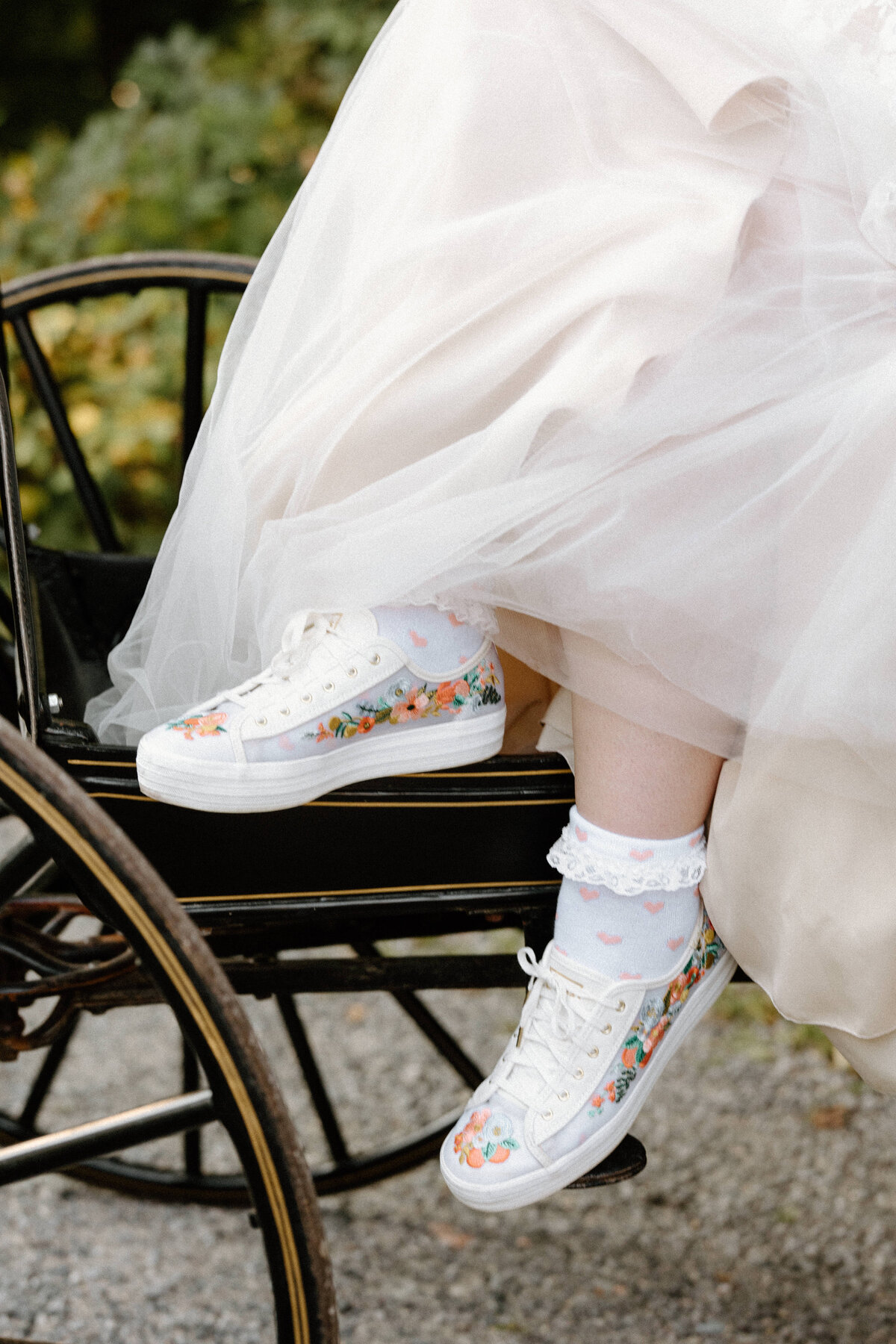 Close-up shot of the bride's sneakers underneath her wedding dress