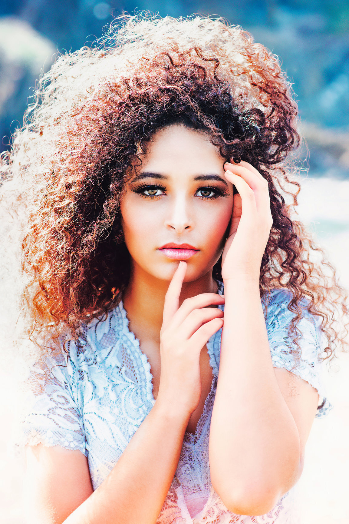 close up of model with curly hair and hand posing