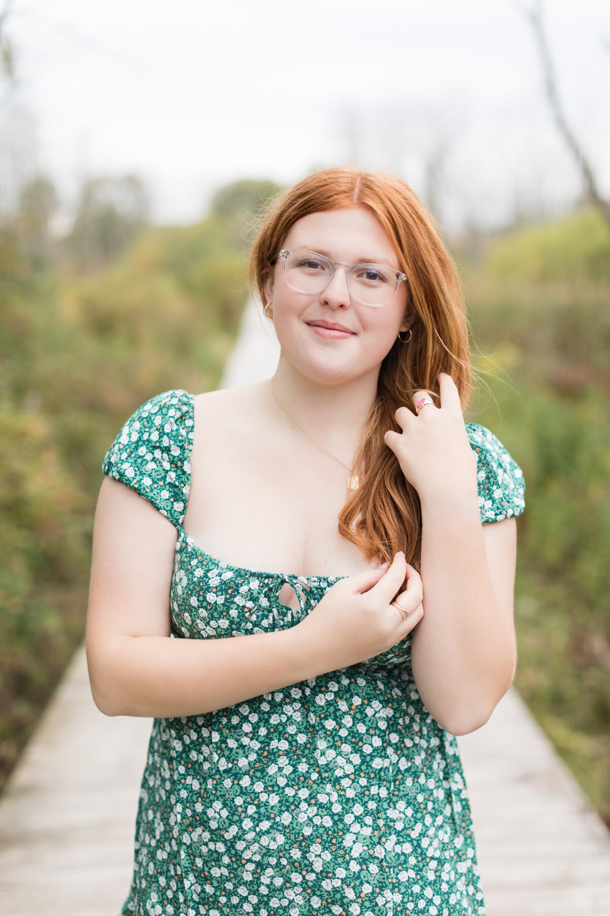 Senior girl standing on a boardwalk smiling at the camera
