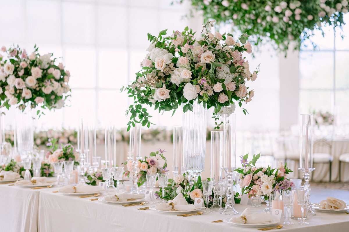 Luxe wedding reception tables adorned with tall lush floral arrangements