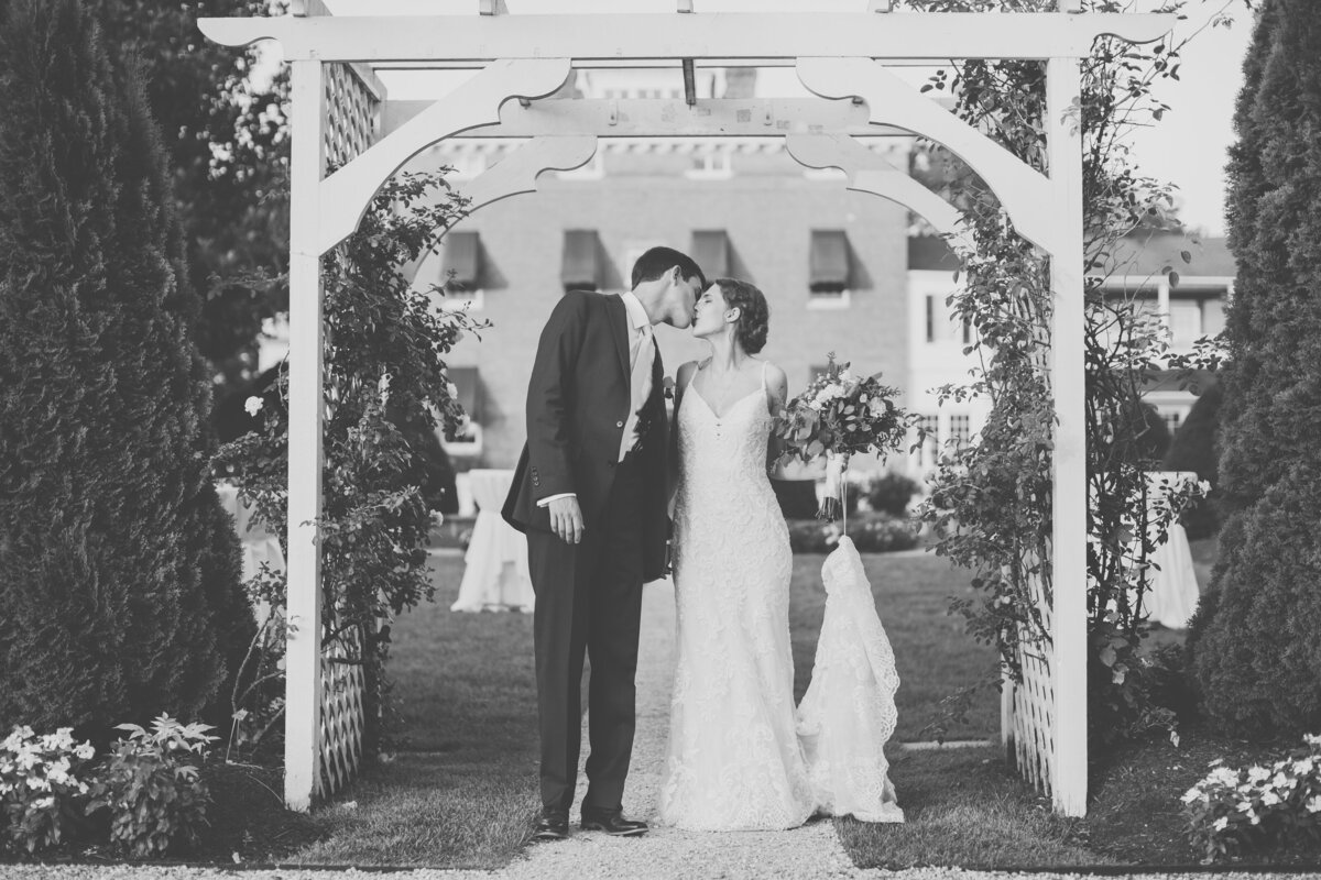 Bride and groom standing under white arbor during outdoor East Coast wedding ceremony in North Carolina.