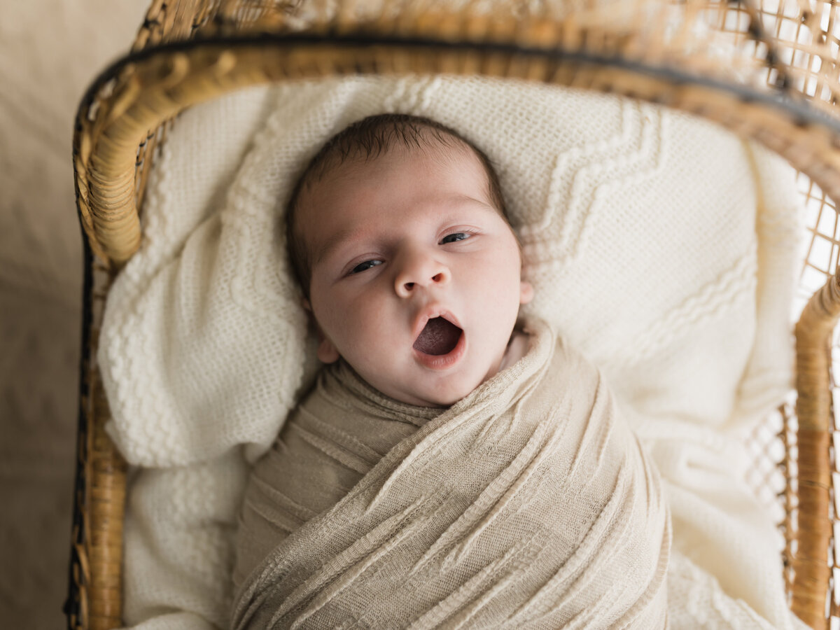 newborn baby boy wrapped in beige swaddle for newborn portraits