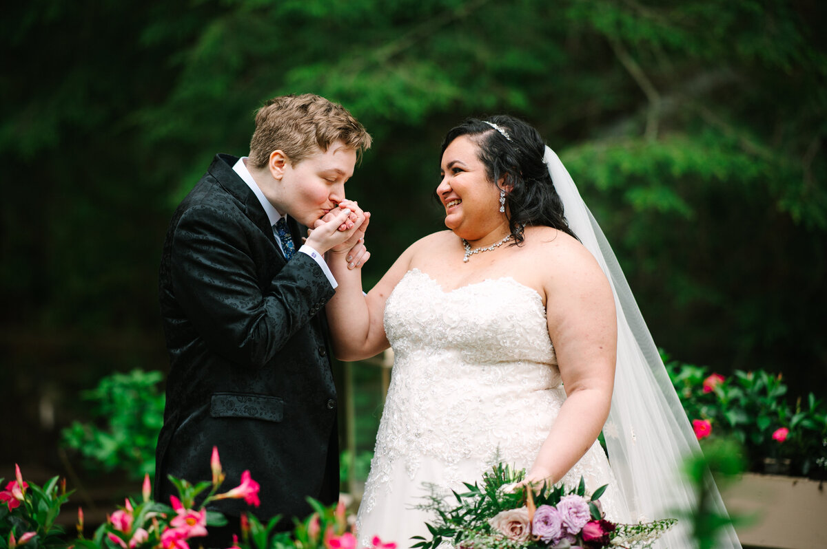 Bride in suit kissing other bride's hand