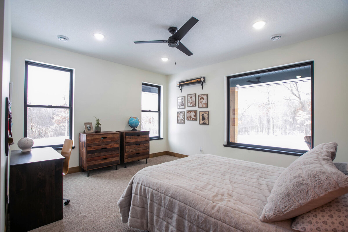 Spacious secondary bedroom in custom Elk River home with dark wood accents and neutral tones