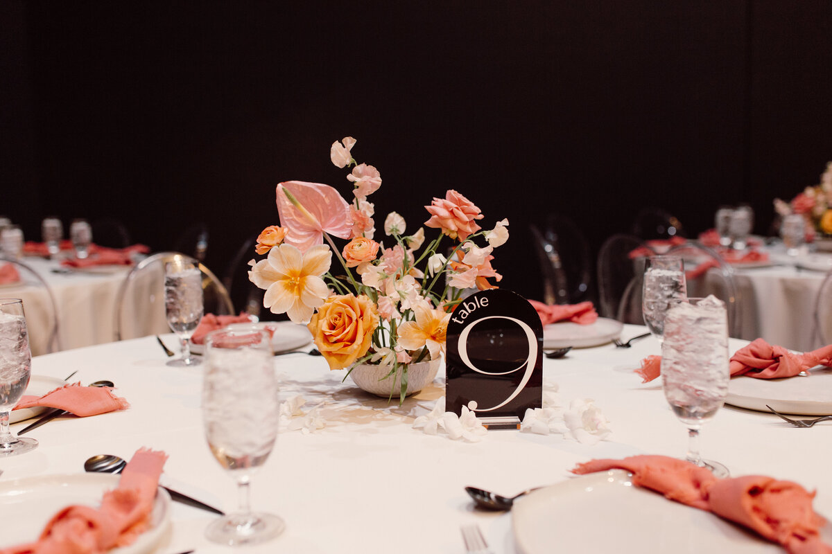 A pink and orange Anthousai floral arrangement on a table for a wedding in OKC.