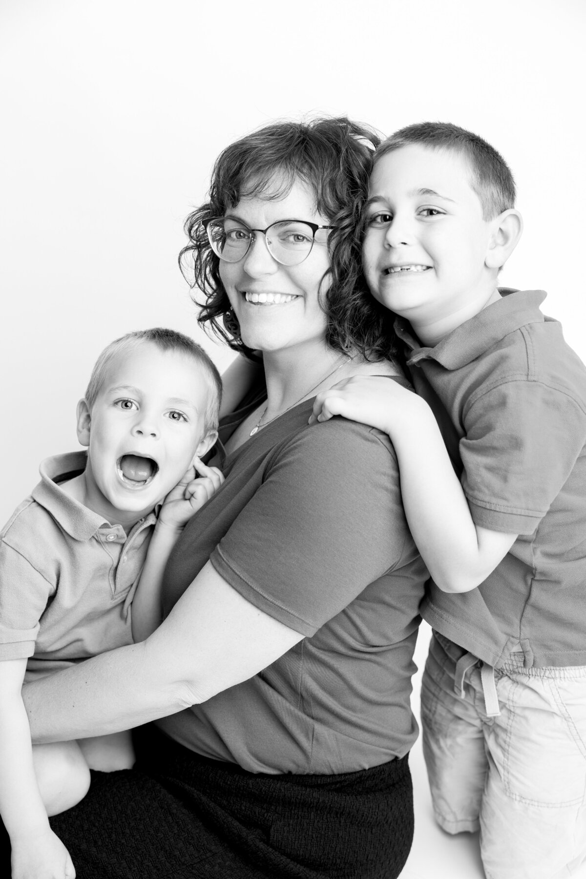 Black and white studio portrait of mom with her two boys