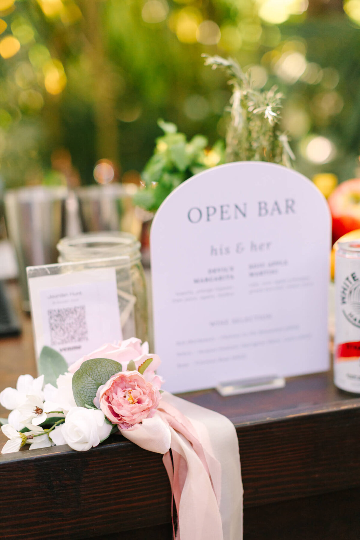 Close-up of a wedding open bar setup with a floral corsage and menu sign.
