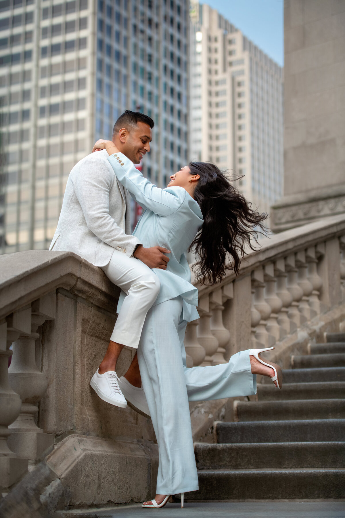 Happy engaged couple smiling and looking at each other while wind is blowing hair in windy city Chicago