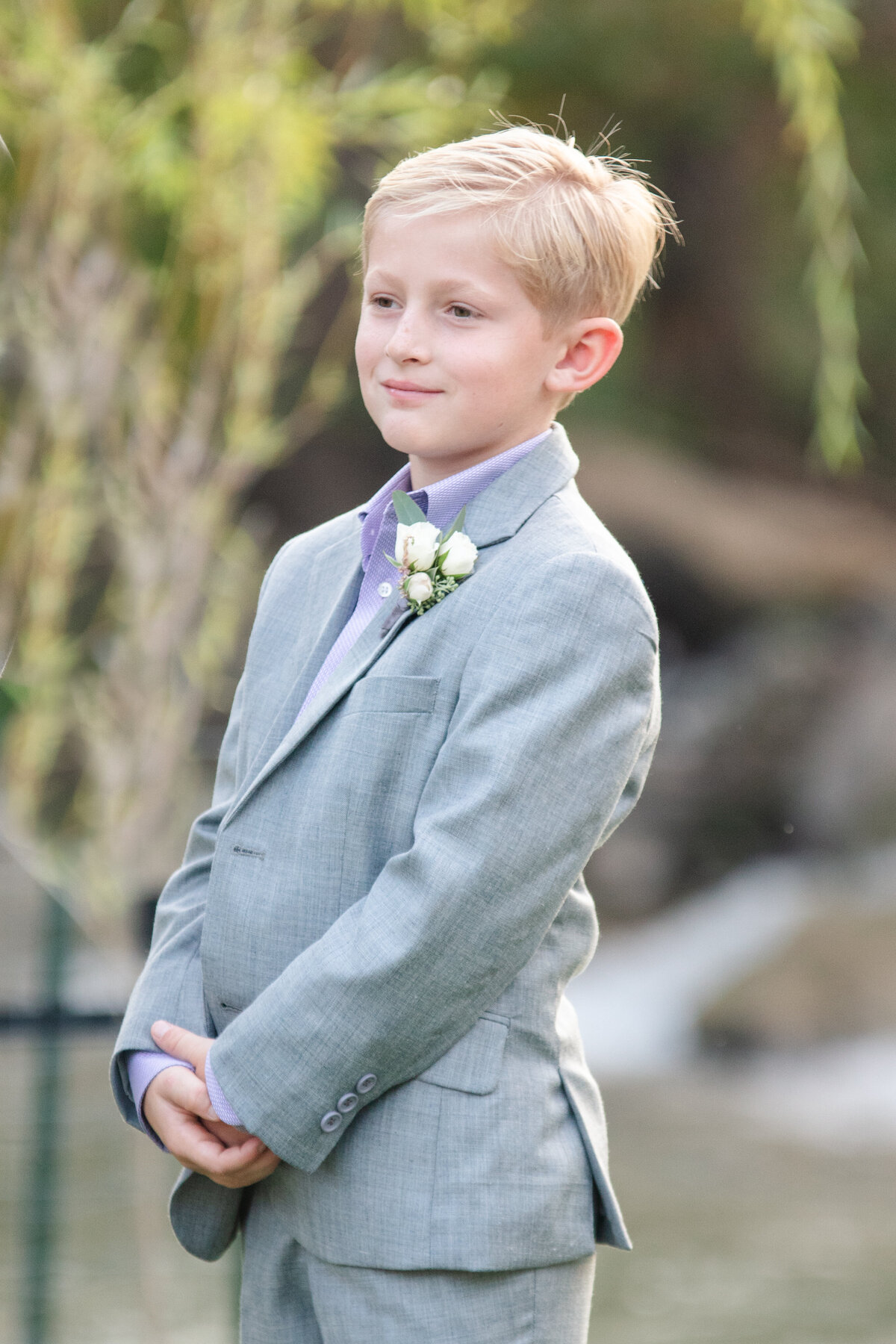 groom's 7 year old son stands in suit smiling at ceremony near Austin Texas