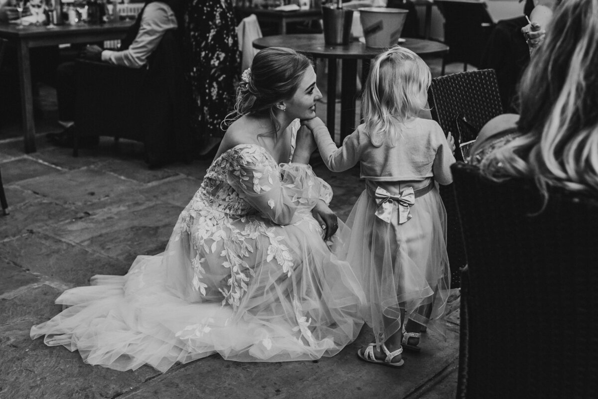 bride crouching to talk to flower girl