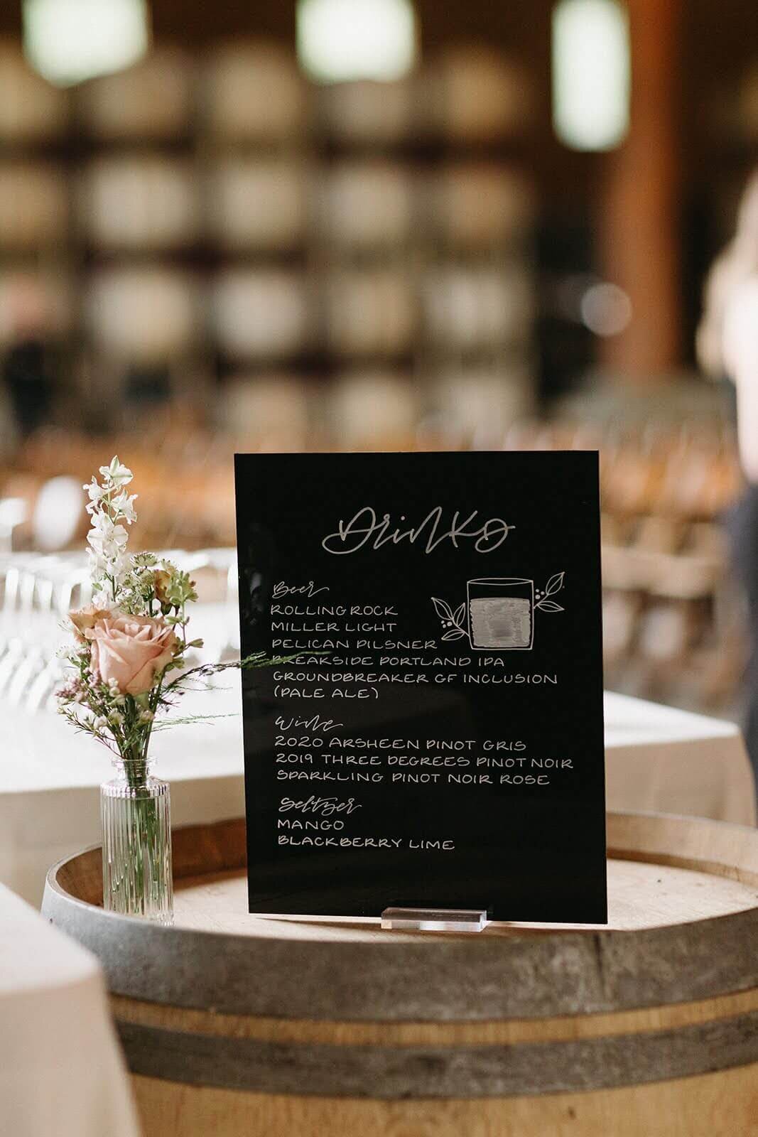 A delicate bud vase arrangement sits next to wedding signage at Maysara Winery.