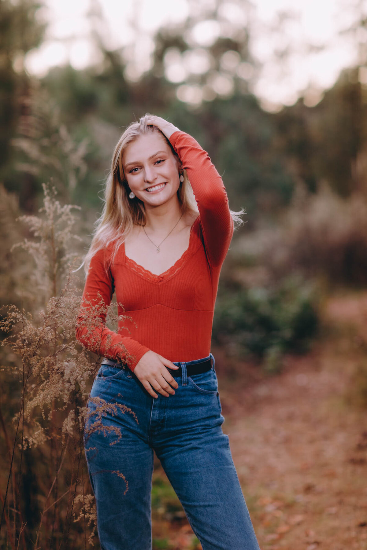 Happy senior portrait of a girl in an orange top with a big smile.