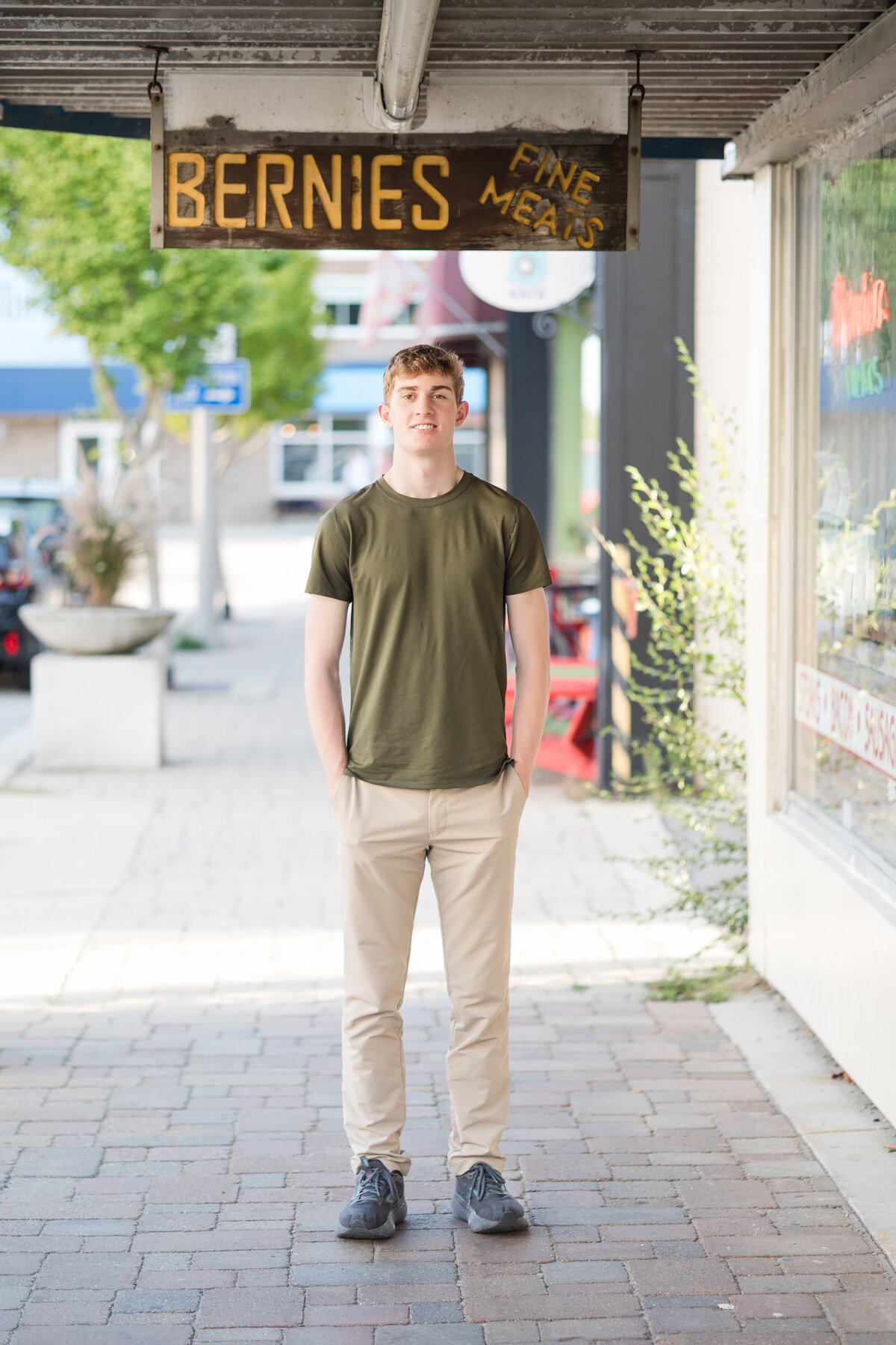 Senior guy standing on the sidewalk and smiling at the camera