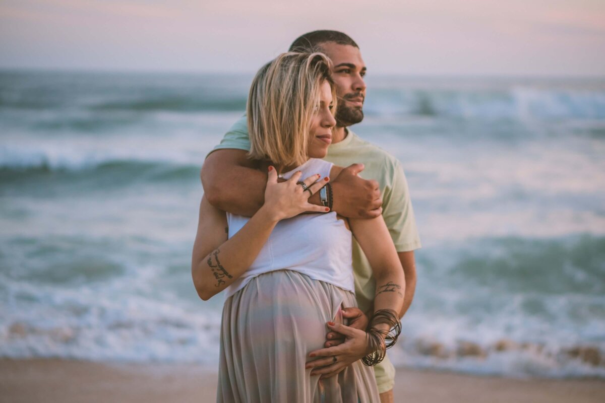 Man Hugging a Pregnant Woman while in the Beach
