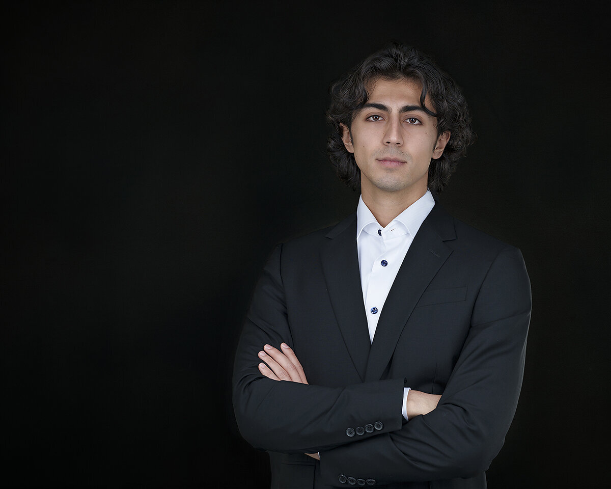 college graduate photoraphed in a black suit on a black background