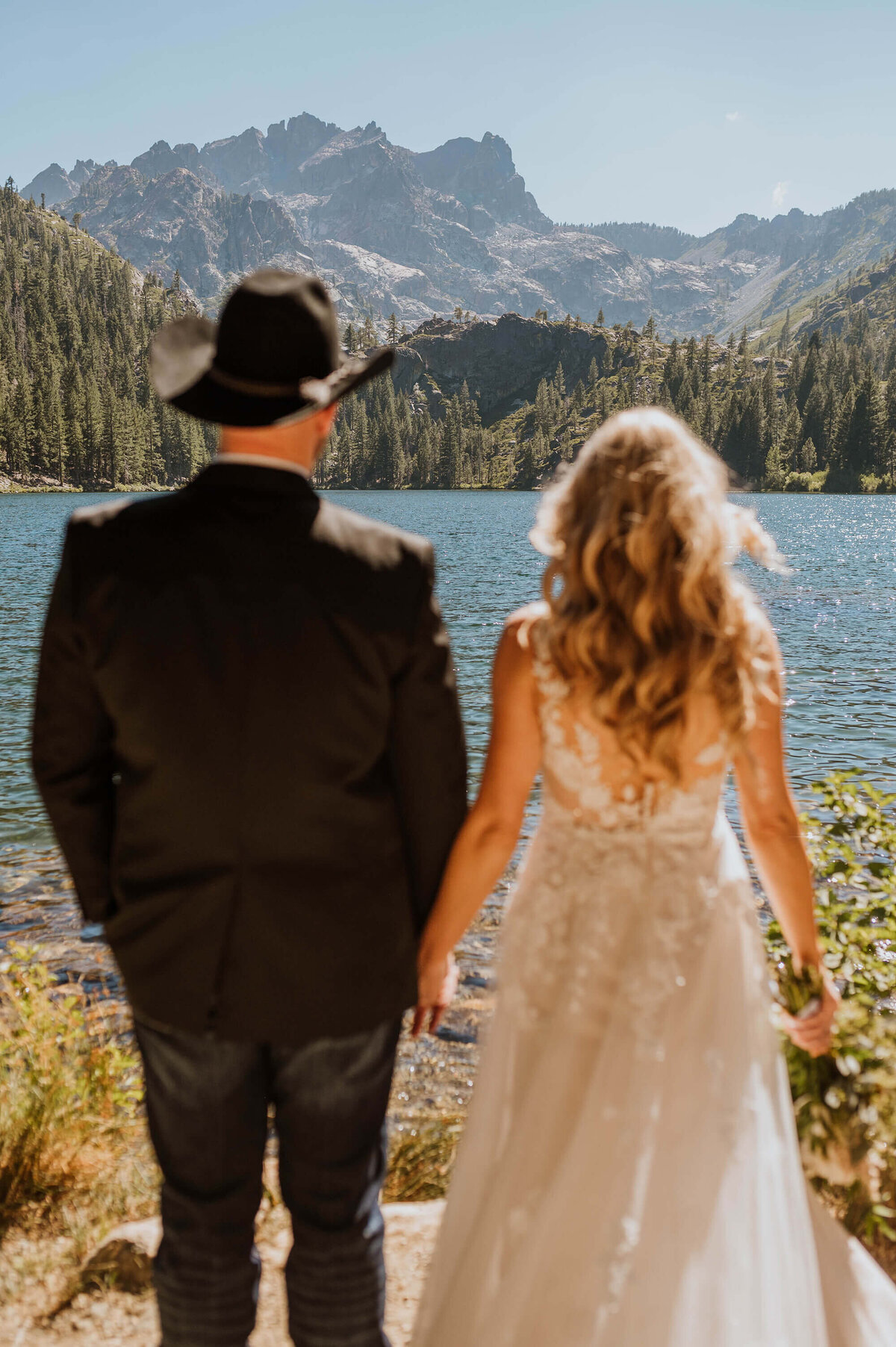 A couple in wedding attire looking out at the mountains.