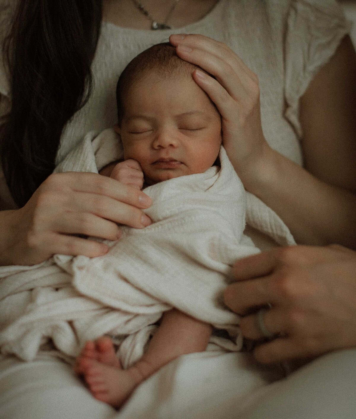 Lifestyle newborn portrait of a baby alone wrapped in soft neutral blankets.