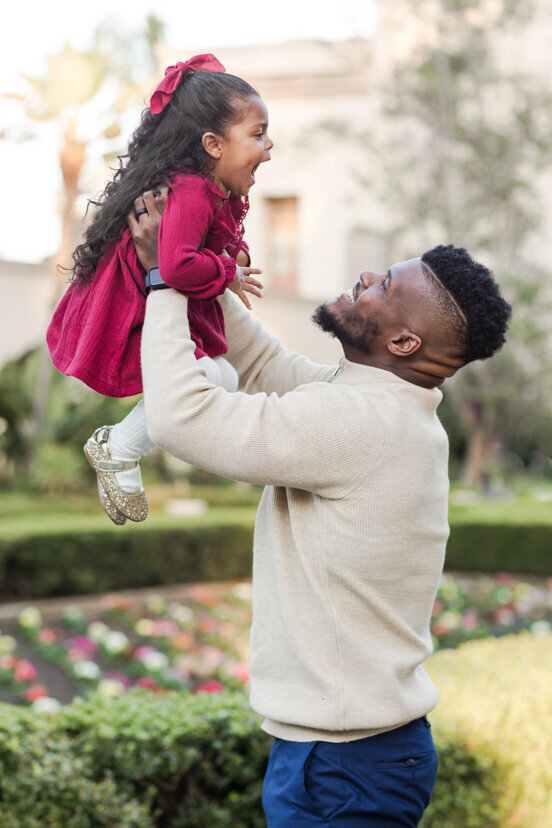 father holding up daughter in Balboa Park