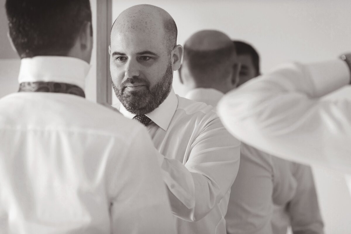 Groomsman helping groom with tie at wedding