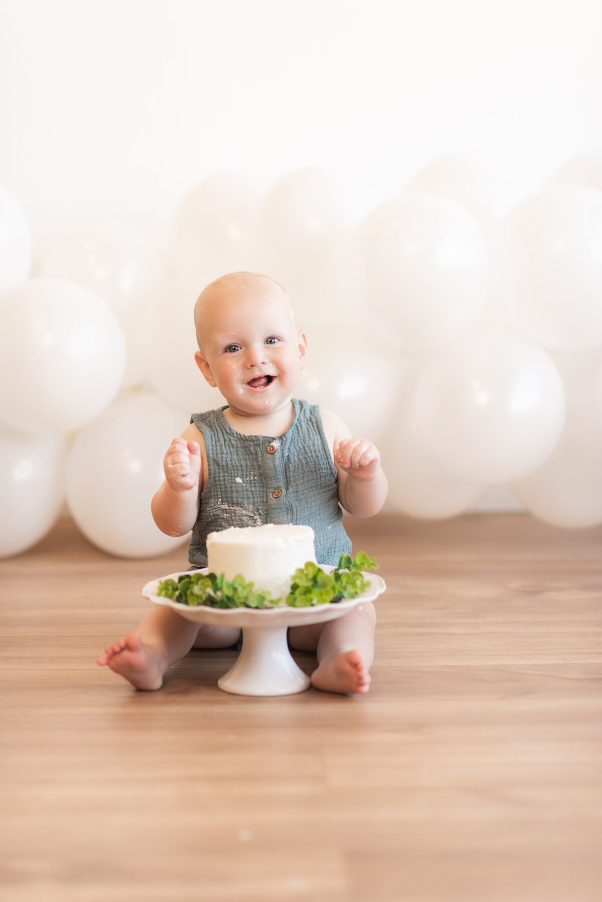 1 year old baby smiles for a cake smash photo session