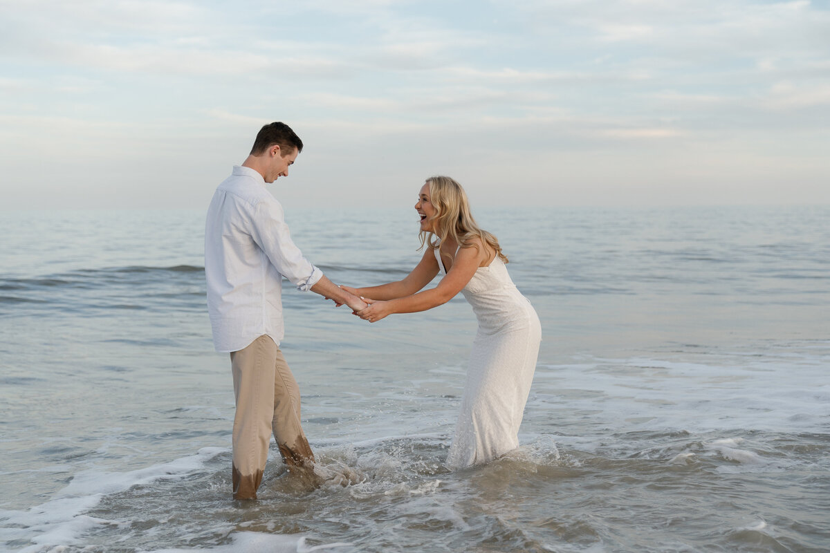Bride and Groom holding hands while splashing in the ocean by Shelby Ann Photos