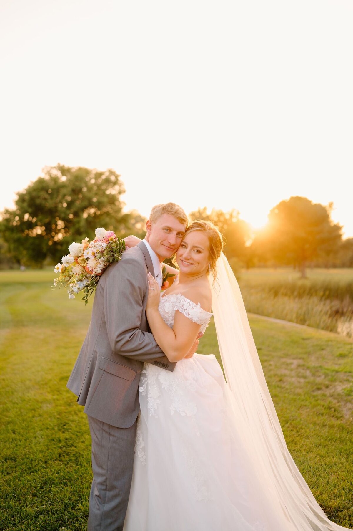 bride and groom smiling with the sun setting in the background