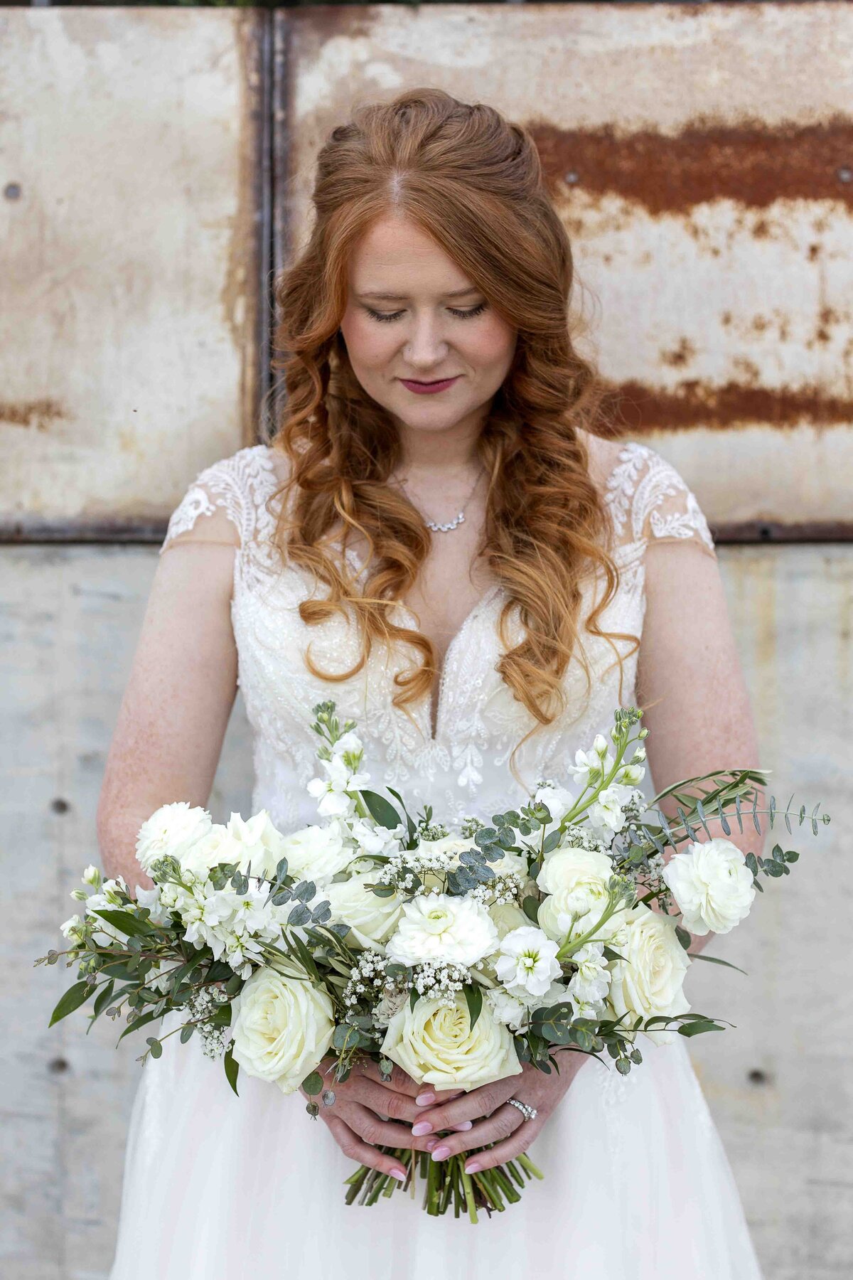Bride looking down at wedding bouquet smiling