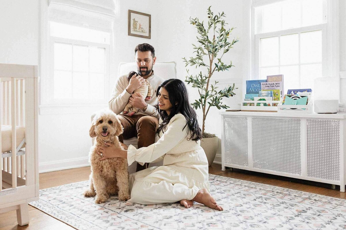 Family with newborn baby and dog in light and bright nursery during Cleveland newborn photography session.