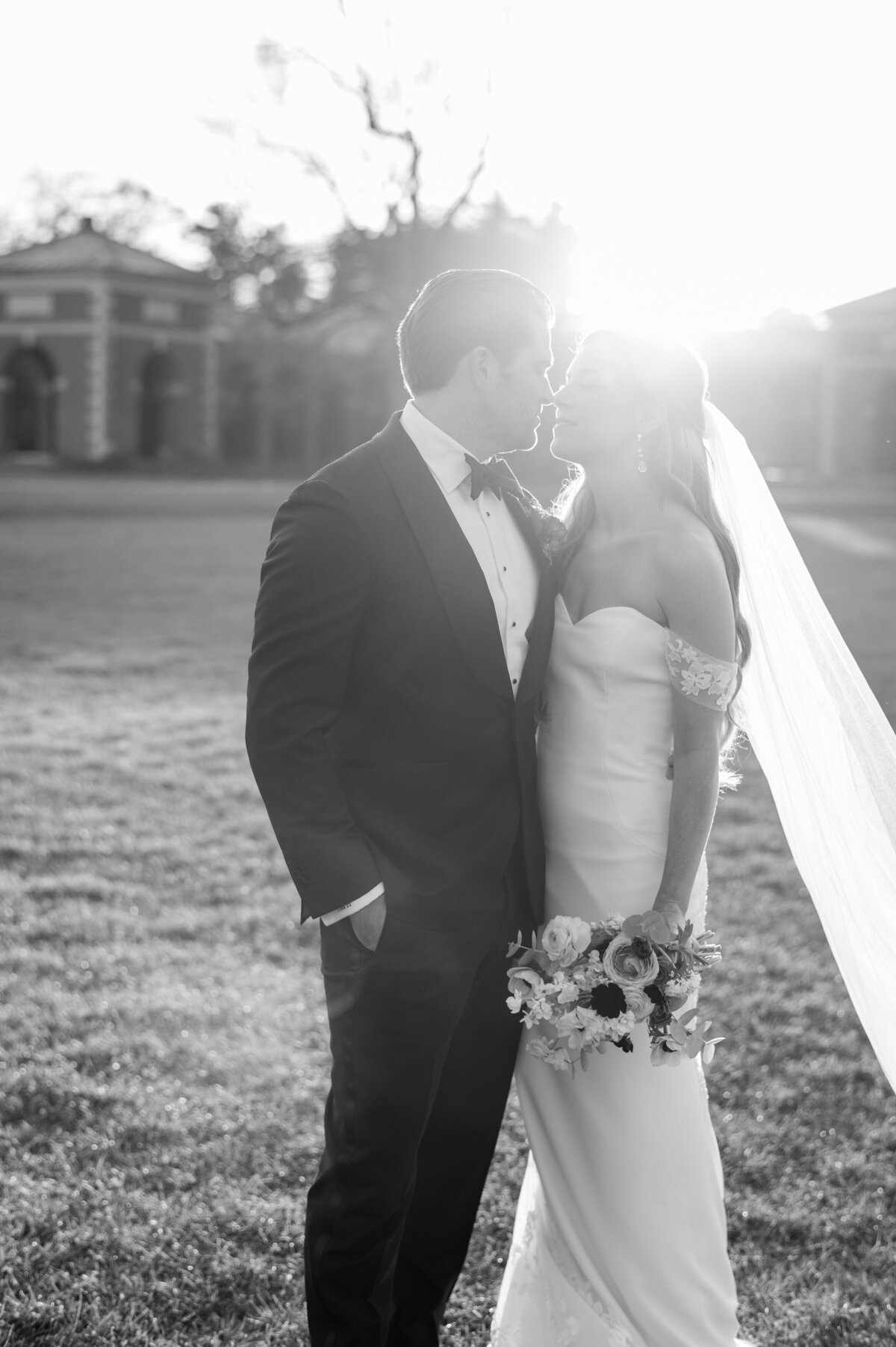 Sun peaks between a kissing bride and groom 