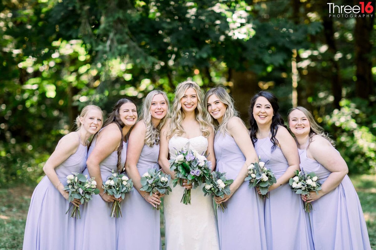 Bride poses with her Bridesmaids in a beautiful green setting