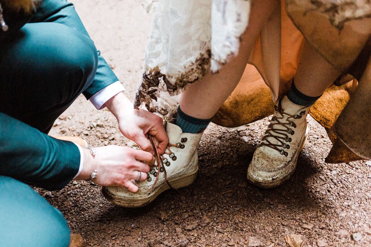 groom tying dirty hiking boots during hiking elopement in Washington State.