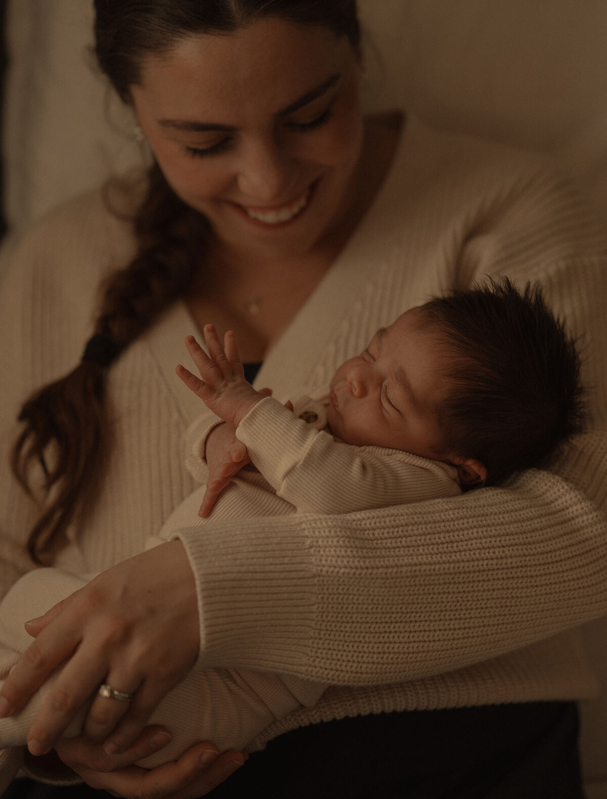 new mother smiling while looking down at her newborn baby
