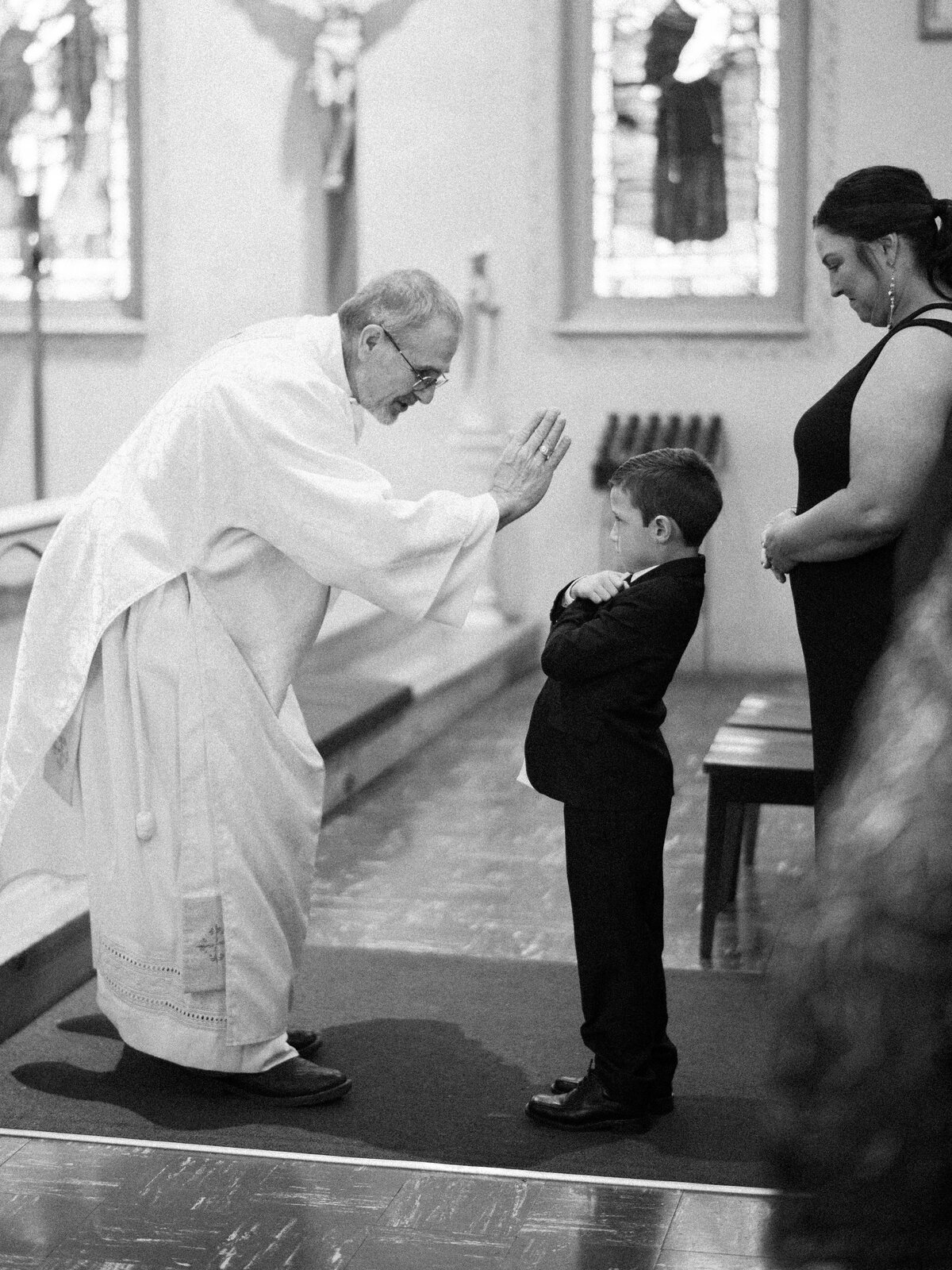 ring bearer receiving a blessing during catholic wedding ceremony