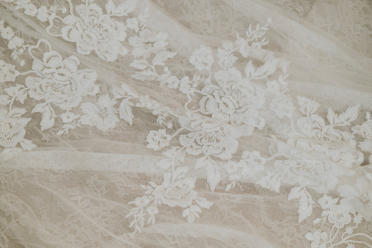 Close up detail of white lace floral appliqué on wedding dress