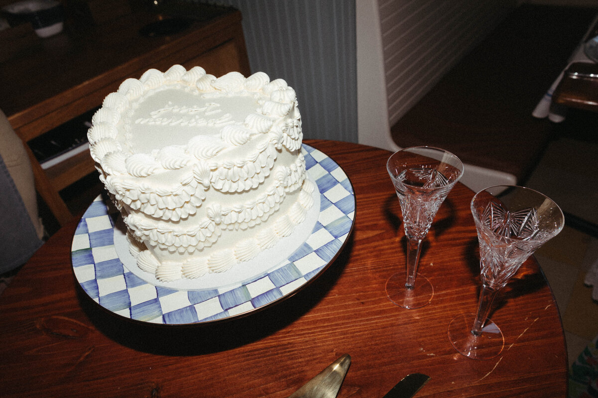 White heart shaped vintage cake on a checkered cake stand with champagne flutes