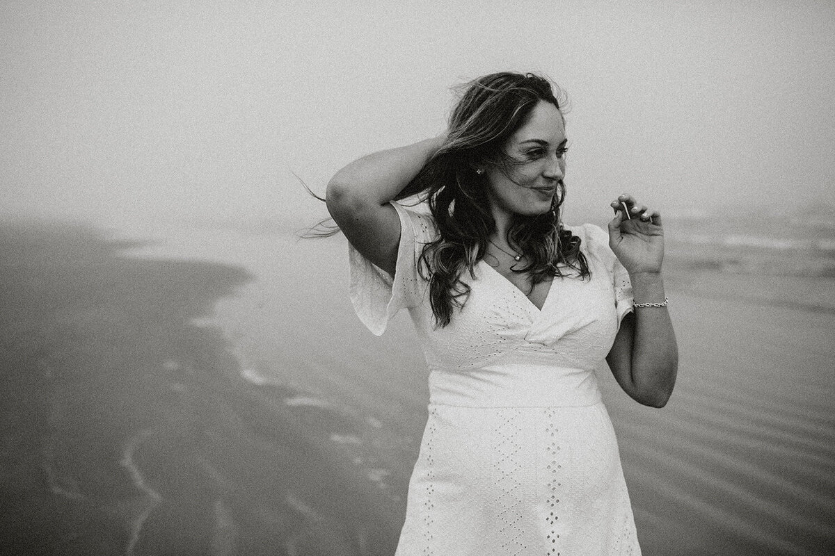 Black and white maternity portrait of a pregnant woman standing on the beach, photographed by San Antonio family photographer Sara James.