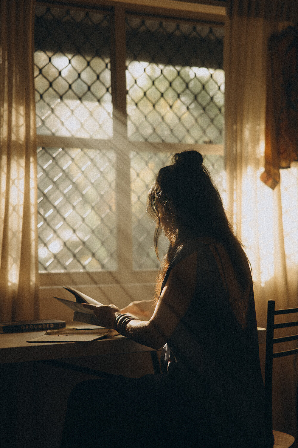 Moody, backlit branding shot of a woman journaling by window light — an intimate portrait by a Sunshine Coast branding photographer.